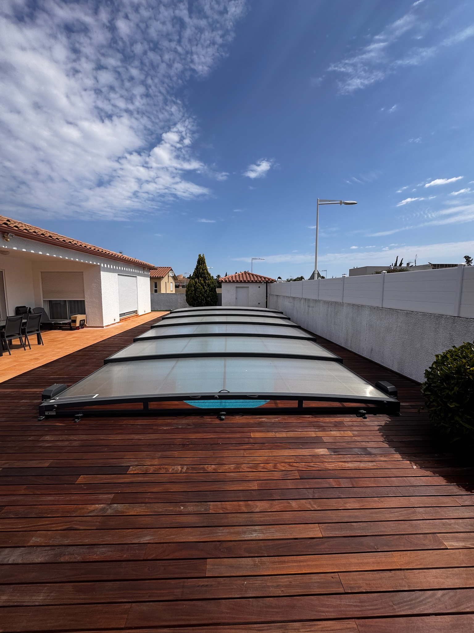 Grande terrasse en bois autour d’une piscine couverte